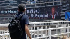 Un hombre camina por un puente frente a pancartas con la imagen del presidente estadounidense Donald Trump y mensajes, en Tel Aviv, el 22 de junio de 2025.