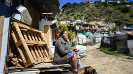 Nury Pérez sentada en la entrada de su casa, decorada con un afiche de campaña en el barrio de Ciudad Bolívar, sur de Bogotá.