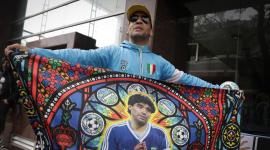 Un aficionado muestra una bandera con la imagen de la leyenda del fútbol argentino Diego Maradona frente al tribunal, antes de una audiencia del juicio por la muerte de Maradona en San Isidro, provincia de Buenos Aires, Argentina,