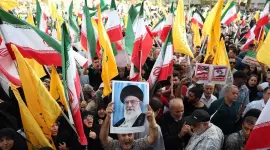 Un iraní sostiene un retrato del líder supremo iraní, el ayatolá Alí Jamenei, entre banderas nacionales de Irán durante una manifestación en Teherán tras el alto el fuego con Israel.
