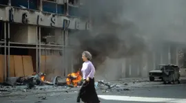 Una mujer corre ante un edificio bombardeado en Sarajevo