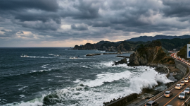 Océano con olas de gran altura que rompen con fuerza contra los muros de contención de concreto.