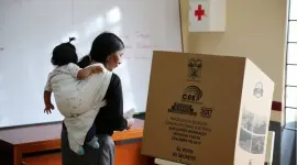 Mujer votando con su bebé cargada en la espalda.
