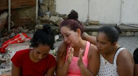People sit next to the rubble of damaged buildings in the aftermath of earthquakes in La Guaira, Venezuela, June 25, 2026. REUTERS/Maxwell Briceno