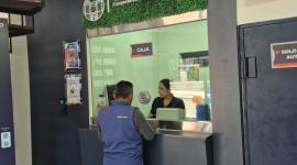 La cajera de una Cooperativa de Ahorro y Crédito atiende a un cliente en una ventanilla.