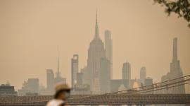 Una persona con el rostro cubierto camina cerca del Puente de Brooklyn mientras el humo de los incendios forestales provenientes de Canadá provoca una densa neblina el 16 de julio de 2026 en Nueva York.