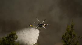 Un helicóptero de extinción de incendios arroja agua sobre una nube de humo de un incendio forestal en la zona de Porto Germeno, a unos 70 kilómetros al noroeste de Atenas