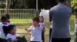 Profesor ayuda a un niño con discapacidad a cruzar la meta en una carrera escolar