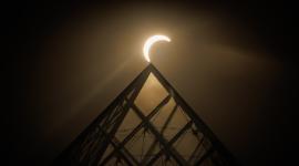 La luna pasa por encima del horizonte solar tras la Pirámide del Louvre durante un eclipse solar parcial en París el 12 de agosto de 2026.