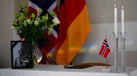 Un retrato del difunto rey noruego Harald V, adornado con una cinta negra de luto, se exhibe junto a flores, velas encendidas, Una bandera noruega y un libro de condolencias, frente a las banderas noruega y alemana, en la Embajada Real de Noruega en Berlín