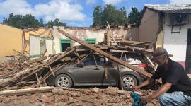 Un hombre pasa en bicicleta junto a una casa derrumbada y un automóvil sepultado bajo los escombros en la localidad de Chitré, en Panamá.