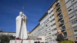 Una mujer reza ante la estatua de Juan Pablo II a las afueras del Hospital Universitario Gemelli, donde el Papa León XIV se recupera tras someterse a una cirugía de pulmón.