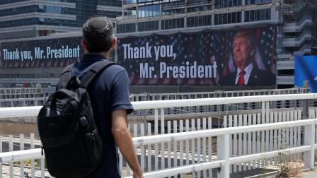 Un hombre camina por un puente frente a pancartas con la imagen del presidente estadounidense Donald Trump y mensajes, en Tel Aviv, el 22 de junio de 2025.