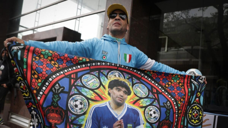 Un aficionado muestra una bandera con la imagen de la leyenda del fútbol argentino Diego Maradona frente al tribunal, antes de una audiencia del juicio por la muerte de Maradona en San Isidro, provincia de Buenos Aires, Argentina,