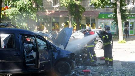 Rescatistas ucranianos extinguen un coche en llamas en el lugar de un ataque con misiles en Sumy, durante la invasión rusa de Ucrania.
