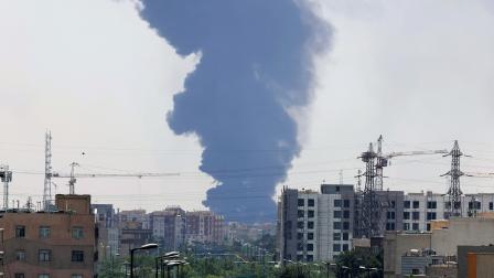El humo de una refinería de petróleo se eleva sobre edificios residenciales en el sur de Teherán, en Irán, este 15 de junio de 2025. Israel atacó sitios relacionados con el programa nuclear y las instalaciones energéticas de Irán.