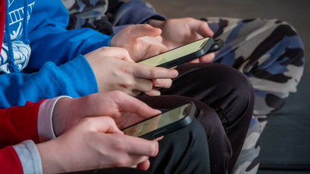 Tres adolescentes manejan sus teléfonos móviles.