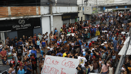 Personas sostienen un cartel contra el gobernador de Río de Janeiro frente a cuerpos sin vida en  la calle.