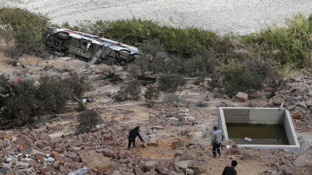 Hombres caminan hacia los restos de un autobús que se precipitó a un barranco de unos 200 metros de profundidad en Arequipa, Perú, el 12 de noviembre de 2025.