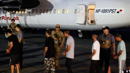 Migrantes caminan frente a un avión tras ser deportados de los Estados Unidos,