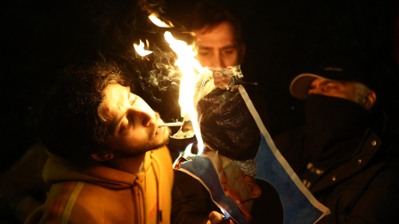 Un hombre prende un cigarrillo en la foto encendida del ayatolá Ali Jamenei.