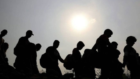 Migrantes caminando bajo el sol.