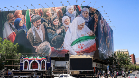Motorists drive their vehicles near a large political billboard along Enghelab Square in central Tehran on May 26, 2026. US forces launched overnight strikes on missile sites in Iran and boats they said were trying to lay mines in Gulf waters, sending oil prices higher on May 26, while diplomats sought a deal to end the war. Iran did not immediately confirm the reported strikes, but state media reported blasts in the southern port city of Bandar Abbas, and the Revolutionary Guards Corps said its forces had downed a US drone entering its airspace and fired at an F-35 fighter jet. (Photo by ATTA KENARE / AFP)