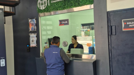 La cajera de una Cooperativa de Ahorro y Crédito atiende a un cliente en una ventanilla.