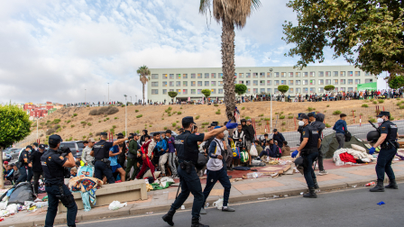 Migrantes esperan en la acera antes de ser registrados en el distrito de Loma Colmenar de Ceuta el 31 de agosto de 2026.