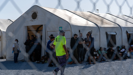 Migrantes sentados junto a las grandes tiendas de campaña en el nuevo campamento de acogida de Los Rosales, donde más de 800 personas fueron trasladadas desde el campamento de Loma Colmenar, en Ceuta.