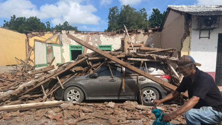 Un hombre pasa en bicicleta junto a una casa derrumbada y un automóvil sepultado bajo los escombros en la localidad de Chitré, en Panamá.