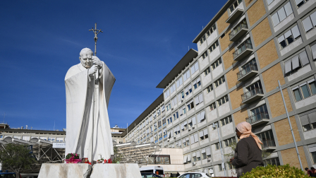 Una mujer reza ante la estatua de Juan Pablo II a las afueras del Hospital Universitario Gemelli, donde el Papa León XIV se recupera tras someterse a una cirugía de pulmón.