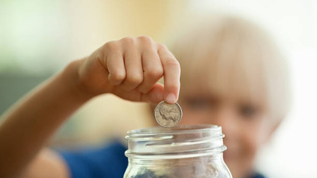 Little boy saving coin in a money ja