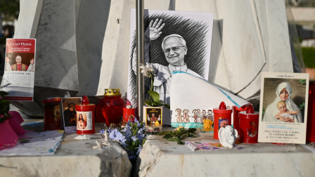Un dibujo del Papa León XIV yace junto a la estatua de Juan Pablo II a las afueras del Hospital Universitario Gemelli.