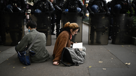 Dos estudiantes protestasn en Francia ante un contingente policial.