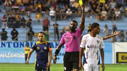El réferi Lenin Quiñónez saca una cartulina amarilla a Bryan Ramírez, futbolista de Liga de Quito, durante el partido jugado el 6 de julio. Atrás de la acción, el capitán 'cetáceo', Édison Vega.