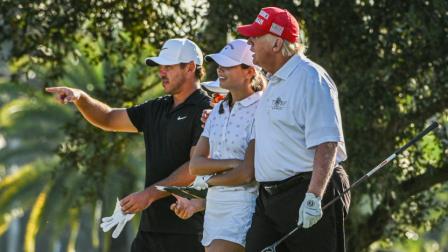 Donald Trump, el golfista estadounidense Brooks Koepka y la nieta del presidente, Kai Trump jugando golf, 27 de octubre de 2022.
