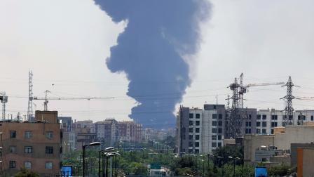 El humo de una refinería de petróleo se eleva sobre edificios residenciales en el sur de Teherán, en Irán, este 15 de junio de 2025. Israel atacó sitios relacionados con el programa nuclear y las instalaciones energéticas de Irán.