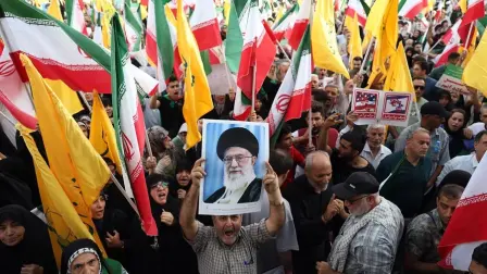 Un iraní sostiene un retrato del líder supremo iraní, el ayatolá Alí Jamenei, entre banderas nacionales de Irán durante una manifestación en Teherán tras el alto el fuego con Israel.