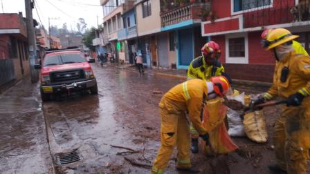Los bomberos de Sangolquí trabajan en destapar alcantarillas para drenar el agua de las calles.