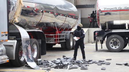Un agente antidrogas de la Policía Nacional de Ecuador encuentra bloques de cocaína en un compartimento oculto de un camión en Tulcán. Más de 2,3 toneladas de cocaína fueron decomisadas en la frontera de Ecuador con Colombia.